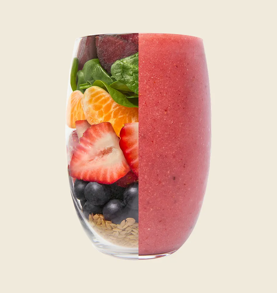 Fresh mixed fruit smoothie in a glass surrounded by raw ingredients.